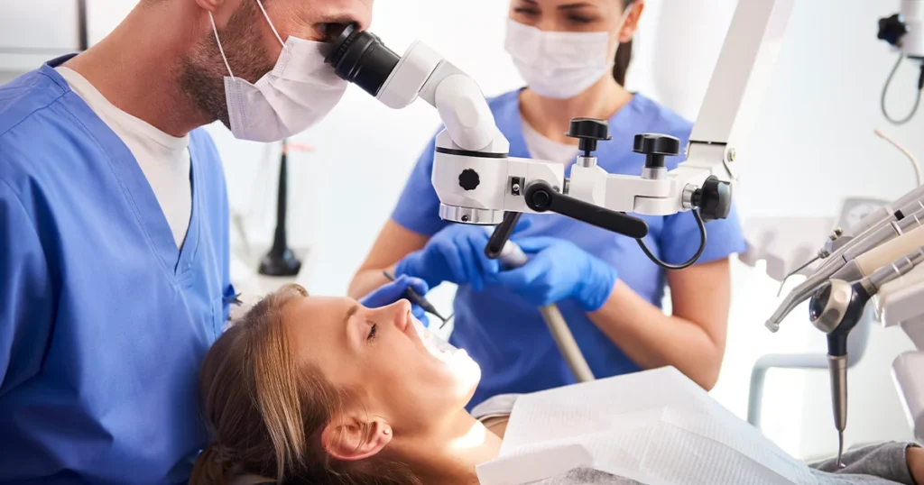 En tandlæge undersøger en patient med et paradentosemikroskop.