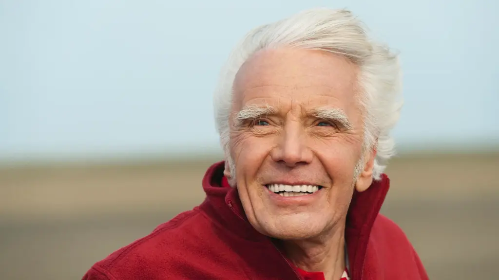 En ældre mand smilende i en rød Tandproteser-jakke.