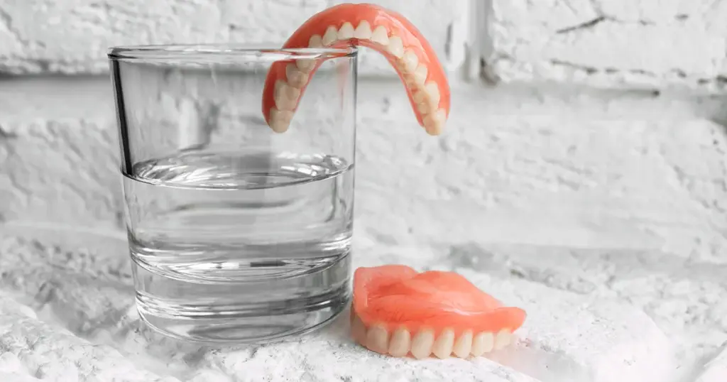 Tandproteser og et glas vand på bordet