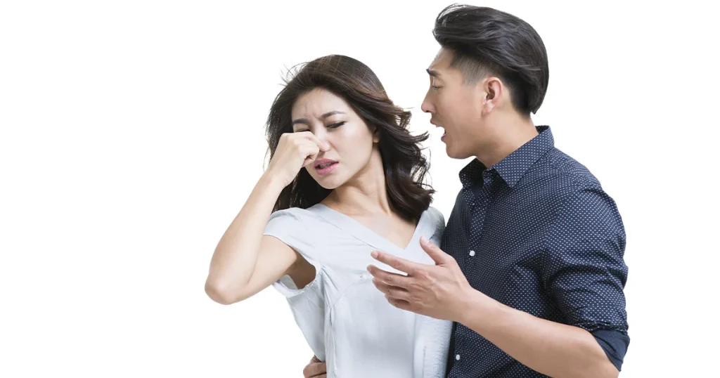 Et billede af en mand og en kvinde, der har dårlig ånde og en kvinde der holder sin næse.